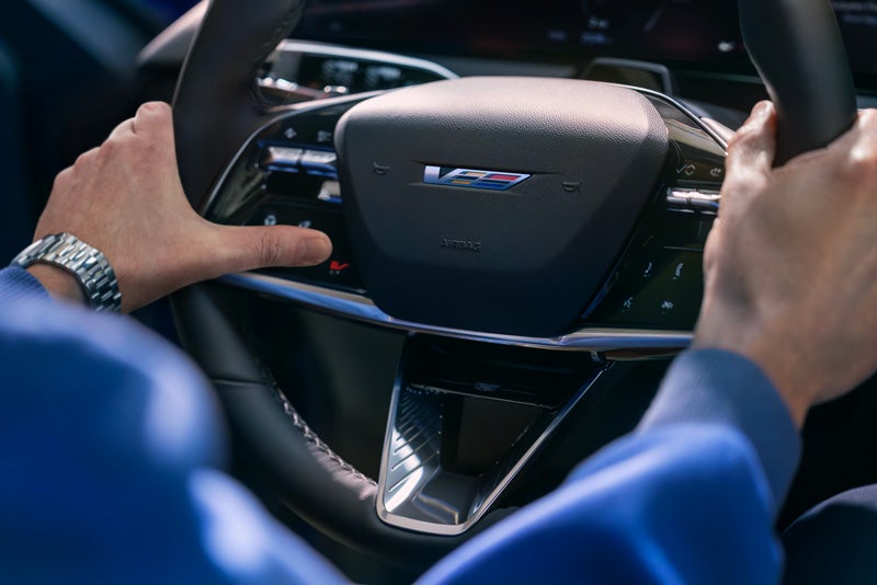 Close-up of a Man About to Press the V-Button on the 2026 OPTIQ-V Steering Wheel | Burke Cadillac in Cape May Court House NJ